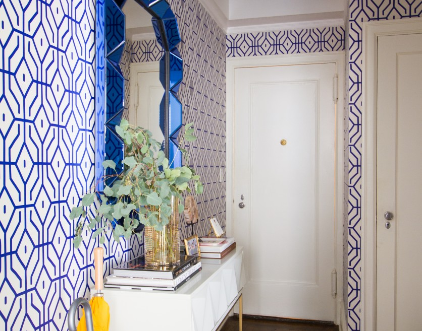 Entryway with bold blue geometric patterned wallpaper.