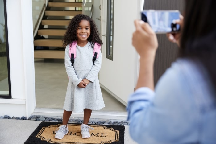 little girl on first day of school by front door